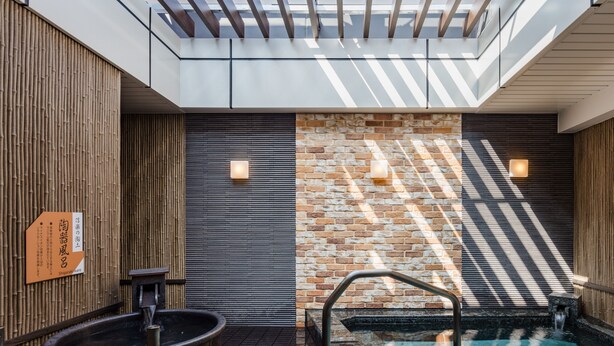 Un espace spa moderne doté d’un jacuzzi, d’une piscine carrelée en pierre et d’un mur en bois agrémenté d’un panneau en bambou.