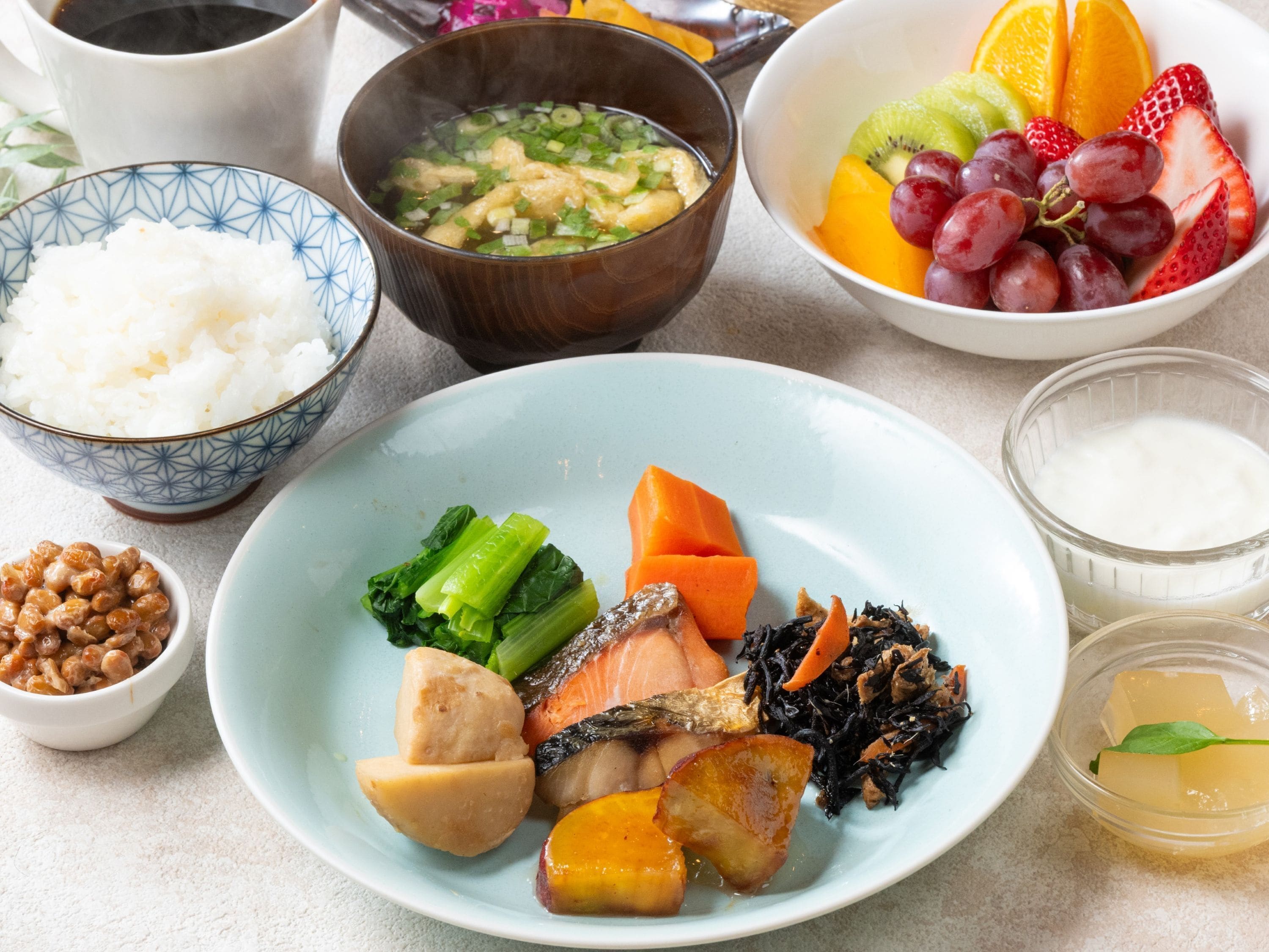 A table with various dishes including rice, soup, fruit, and vegetables.