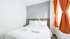 A hotel room with a large bed, white linens, a wooden headboard, and orange curtains. - Eighty Eight Hotel (Koronadal)