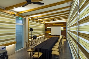 Un salón de conferencias con una larga mesa, sillas, una pizarra y una puerta de salida.