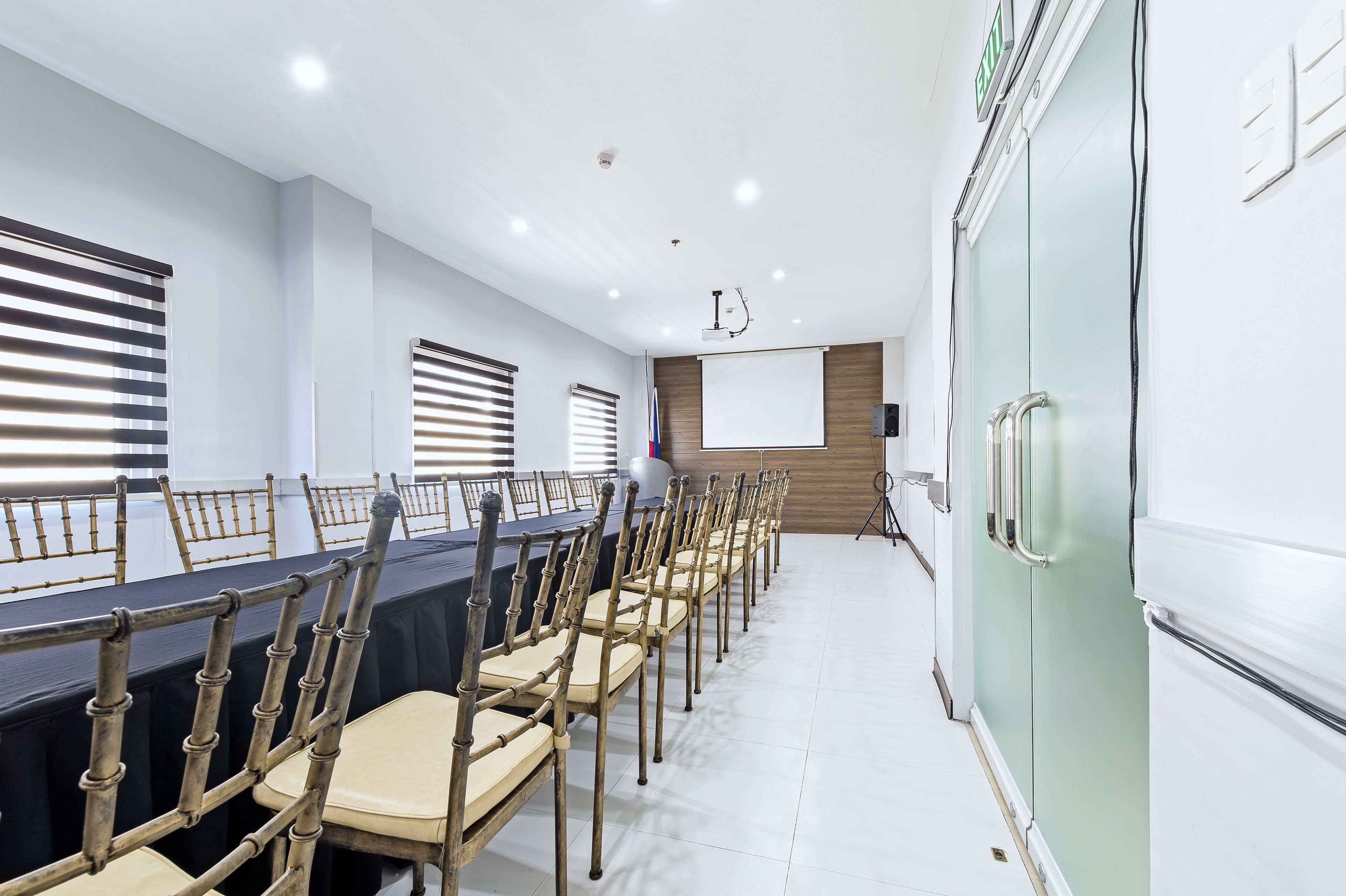 A conference room with a long table, chairs, a projector screen, and a whiteboard.