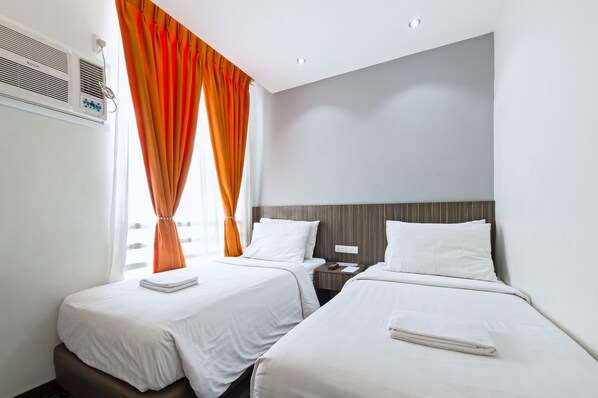 A hotel room with two single beds, a control panel, and a window with orange curtains. - Eighty Eight Hotel (Koronadal)