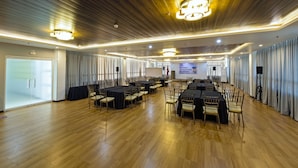 A conference room with wooden floors, tables with black tablecloths, and chairs. - Eighty Eight Hotel (Koronadal)