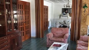 Un salón amplio con techo alto, un mueble grande de madera y un conjunto de sofá rosa.