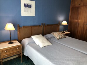 A neatly made bed with a wooden headboard, two bedside tables with lamps, a wooden wardrobe, and a framed artwork on the wall. - Casa María (Artana)