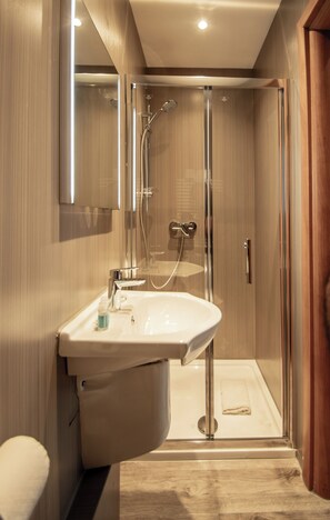A modern bathroom with a glass-enclosed shower, a pedestal sink, and a toilet. - New Kent Apartments (London)