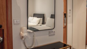 A hotel room with a bed, a mirror, a hairdryer, and a small table. - New Kent Apartments (London)