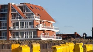 A multi-story building with balconies, situated on a sandy beach with yellow mailboxes. - Strandhaus Christiansen (Cuxhaven)