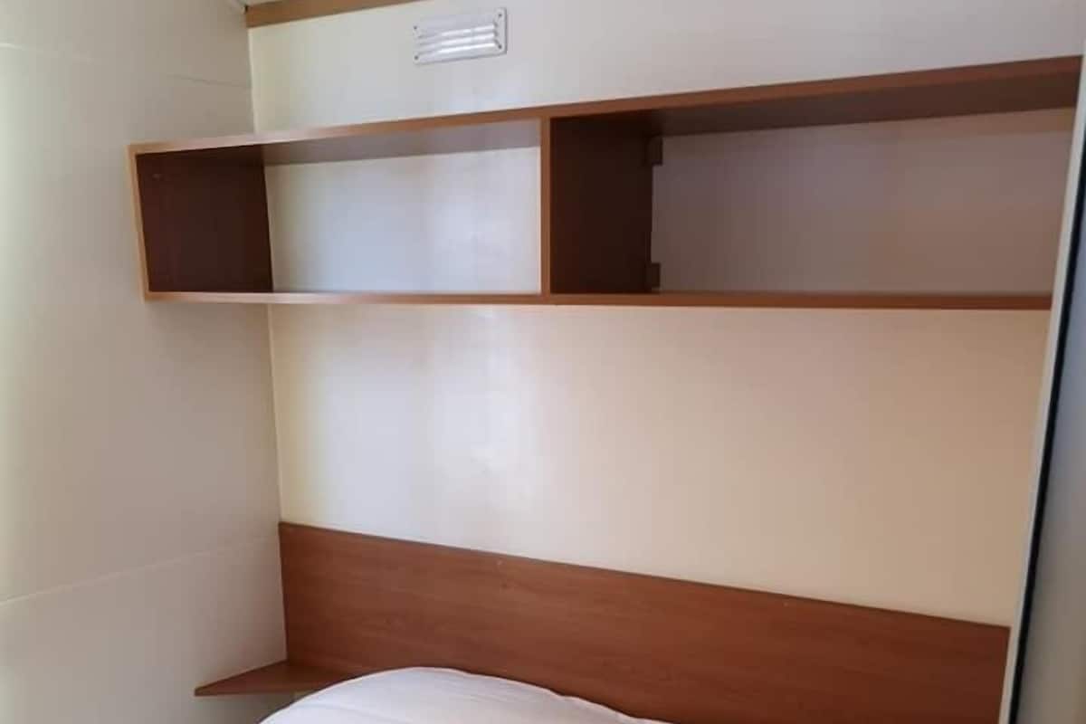 Una camera da letto con un letto, una testiera in legno e scaffali a muro.