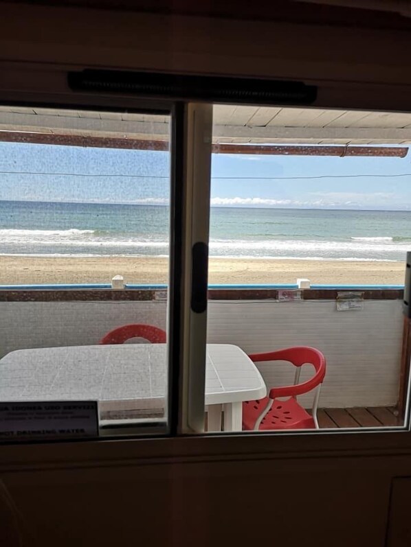 A view from inside a room with a window overlooking a beach. - Camping Hippocampus (Fondi)
