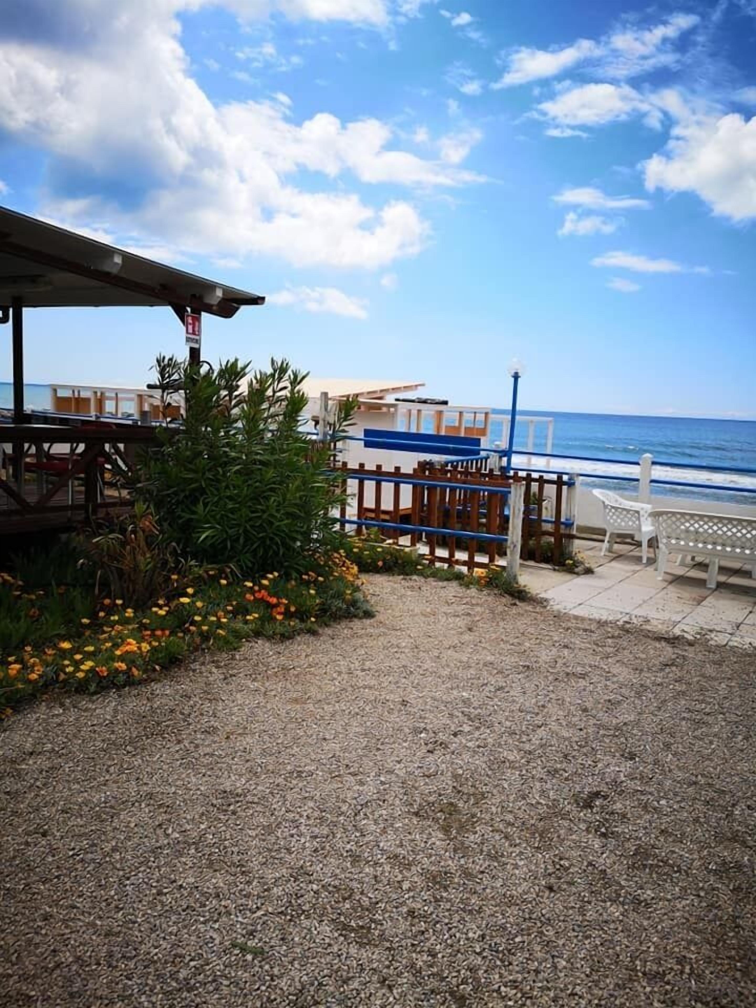 A coastal area with a gravel path leading to a wooden deck overlooking the sea.