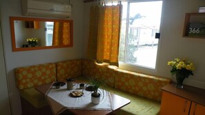 Una habitación acogedora con sofá, una mesita, una ventana con cortinas, un espejo y un armario.