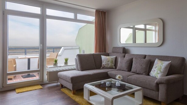 A modern living room with a large window, a sofa, a coffee table, and a small side table.