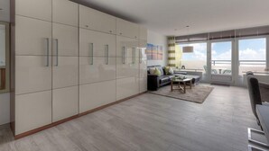 A modern living room with a large wardrobe, a sofa set, and a dining area.
