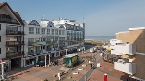 A coastal hotel with multiple floors, outdoor seating, and a view of the beach.