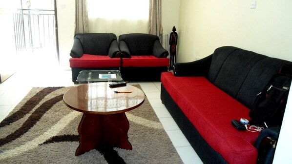 A living room with a red sofa, a black sofa, a coffee table, and a small table with a remote control.