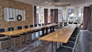 A conference room with a long table, chairs, and a stone wall. - Merfelder Hof (Dülmen)