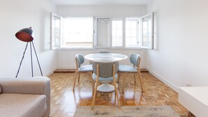 Uma sala de jantar moderna com uma mesa redonda, quatro cadeiras e um abajur.