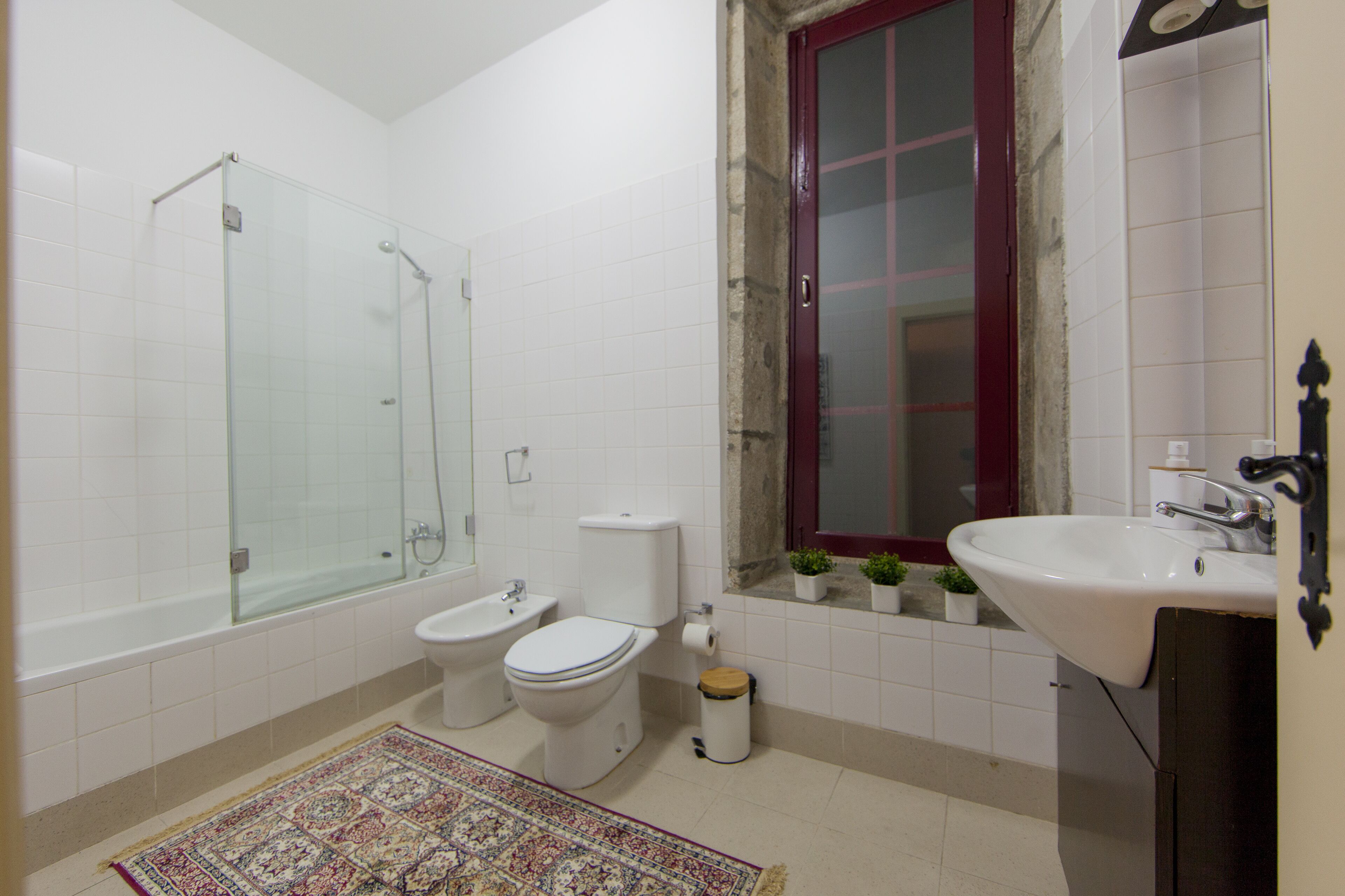 A bathroom with a glass-enclosed shower, a toilet, and a sink.
