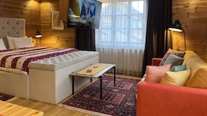 A cozy room with a bed, a sofa, a TV mounted on the wall, and a window with curtains. - Chalet Kolasin Montenegro (Kolašin)