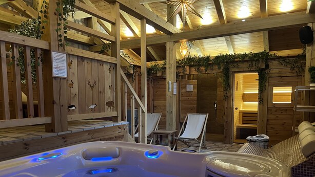 A hot tub with a wooden deck and a wooden wall with animal carvings. - Chalet Kolasin Montenegro (Kolašin)