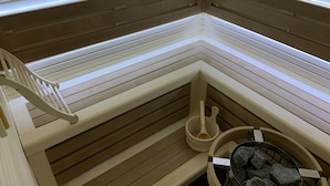 A sauna with wooden benches, a wooden bench with a backrest, and a stone-filled basin. - Chalet Kolasin Montenegro (Kolašin)