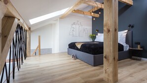 Ein modernes Schlafzimmer mit Dachfenster, einem Bett mit dunklem Kopfteil und einer Wandleuchte.