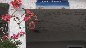 Fachada de un edificio con un letrero que dice "BLUE DREAMS" y una estatua blanca de una mujer.
