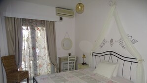 Un dormitorio con una cama, una silla, una mesita de noche, una lámpara y un aire acondicionado instalado en la pared.