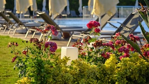A poolside area with lounge chairs and umbrellas, surrounded by lush greenery and flowering plants. -  Acroter Hotel & Spa Datca (Datça)