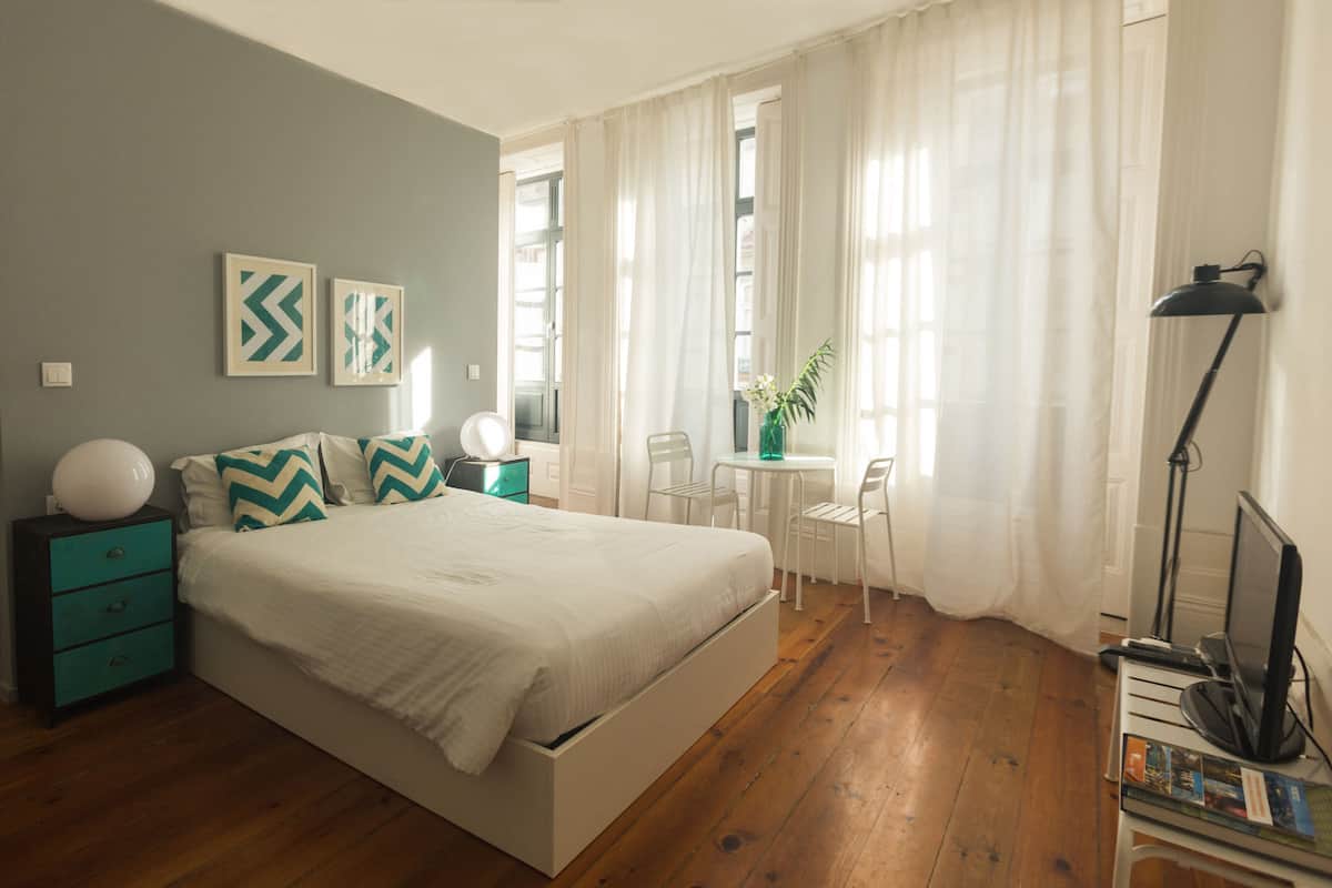 A bedroom with a bed, a nightstand, a desk, and a chair.