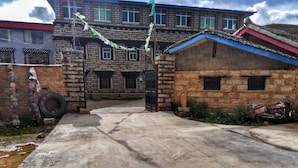 A traditional building with a stone facade, a gated entrance, and a paved courtyard.