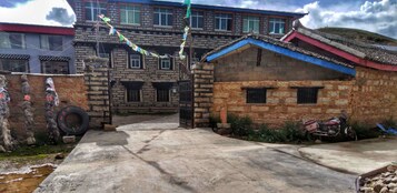 Un edificio tradicional con fachada de piedra, entrada porticada y patio empedrado.