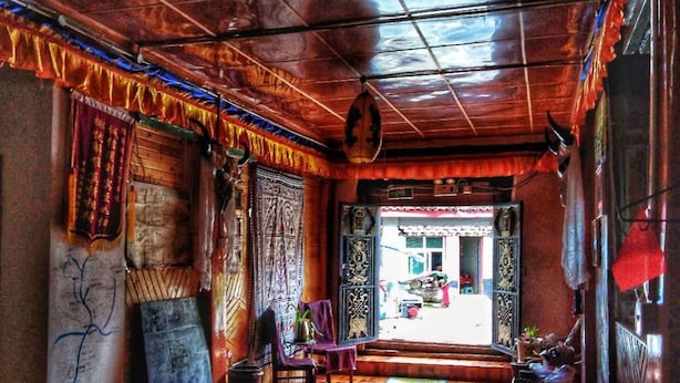 A hallway with a polished wooden floor, traditional decor, and a hanging light fixture.
