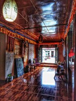 Un pasillo con piso de madera pulida, decoración tradicional y una lámpara colgante.