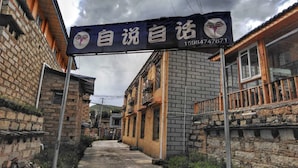 A narrow alleyway with traditional buildings, a sign with Chinese characters, and a telephone number.