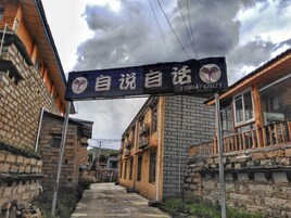 Un callejón estrecho con edificios tradicionales, un letrero con caracteres chinos y un número de teléfono.