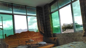 A bedroom with a wooden bed, a window with a view of mountains, and a patterned bedspread.