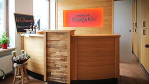 Una recepción con diseño de madera, un cartel con el nombre del hotel y una pizarra con la contraseña de Wi-Fi.