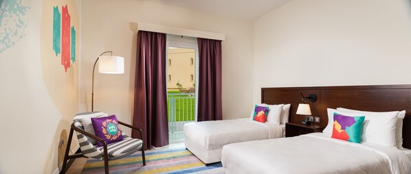 A hotel room with two beds, a chair, a lamp, and a view of a balcony. - Atana Stay Salalah (Salalah)