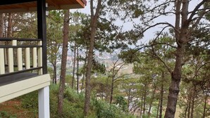 A wooden bench overlooking a forested area with a view of a distant town. - Auberge Plain of Jars - Phouphadeng (Phonsavan)