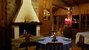 A cozy dining area with a stone fireplace, wooden walls, and a table set for two. - Auberge Plain of Jars - Phouphadeng (Phonsavan)