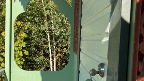 Eine grüne Tür mit Fenster, einem Metallbeschlag und einem Holzboden.