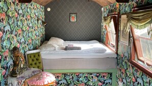 Ein Zimmer mit einem Bett, einem kleinen Tisch und einer dekorativen Statue.