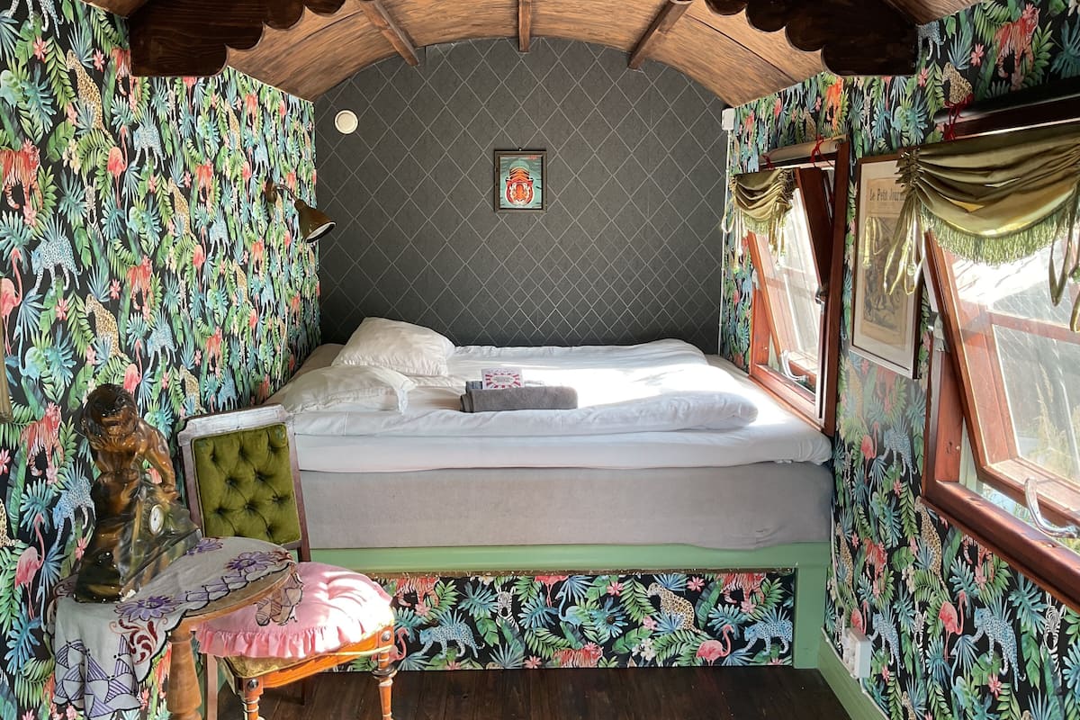 A room with a bed, a small table, and a decorative statue.