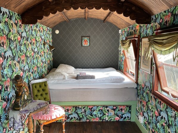 Una habitación con una cama, una mesita y una estatua decorativa.