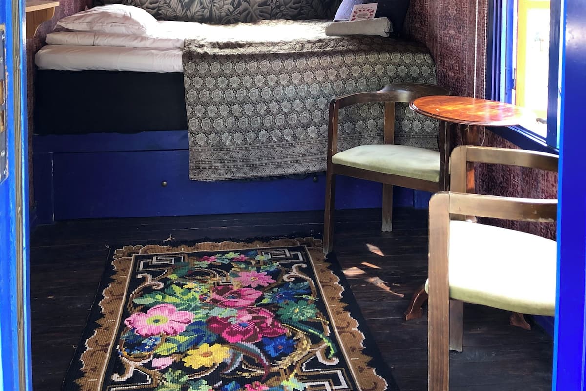 A cozy room with a bed, a chair, a small table, and a window with a view.