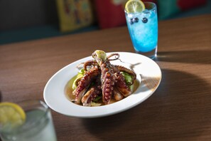 A plate of octopus with lemon on a wooden table. - Atana Stay Al Ashkarah (Al Ashkharah)