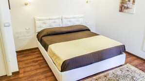 Una cama bien hecha con una colcha marrón y color beige, almohadas blancas y dos lámparas de pared.