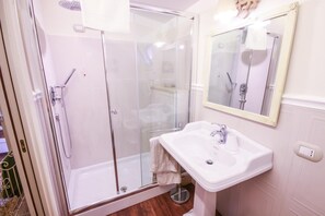 A bathroom with a glass-enclosed shower, a white sink, and a mirror. - 96 Guest House (Reggio Calabria)